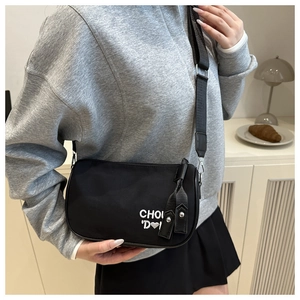 Détail du sac bandoulière en nylon noir avec broderie blanche CHOU et cœur sur le D