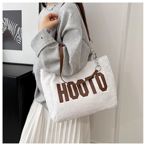 Detail of white plush tote bag with HOOTO letter patch and silver metal chain strap