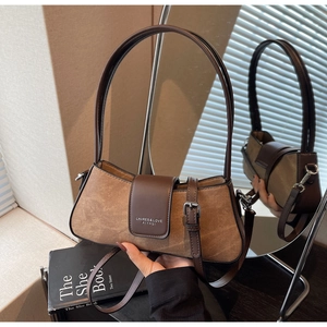 Detail of caramel suede baguette bag showing the magnetic buckle and textured leather finish