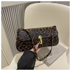 Detail of trendy leopard print baguette bag featuring a gold oval twist lock closure