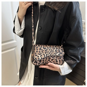 Detailed view of women's leopard print crossbody bag with textured fabric and slim strap