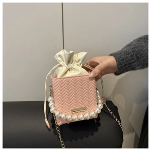 Pink woven mini bucket bag with pearl handle, gold chain and cream drawstring liner details