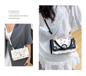 Detail of cherry print crossbody bag with woven handle and gold floral clasp