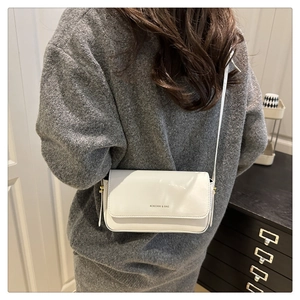 Rear view of white leather crossbody bag showing actual size on person in a home setting