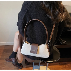 Detail of minimalist cream and brown baguette bag with adjustable strap and brand logo