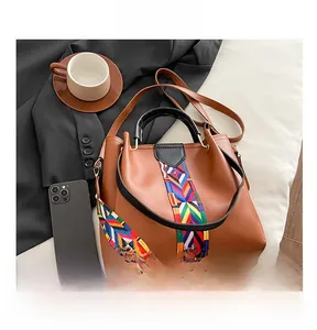 Top view of brown leather handbag with ethnic colorful woven strap and accessories