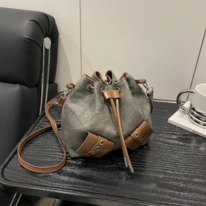 Fashionable grey canvas drawstring bucket bag with brown leather trim and dual pockets