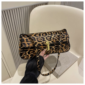 Detailed close-up of leopard print baguette bag with gold hardware on a white chair