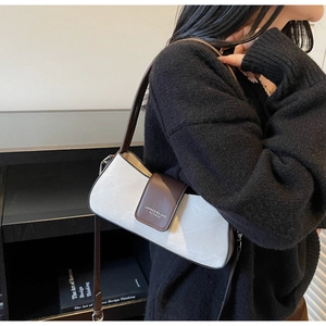 Detail view of contrast leather baguette bag with adjustable straps and metal hardware