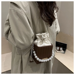 Detail of crossbody bag with pearl handle and contrast weave texture