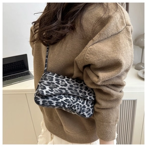 Detailed view of leopard print shoulder bag worn by model in a minimalist room setting