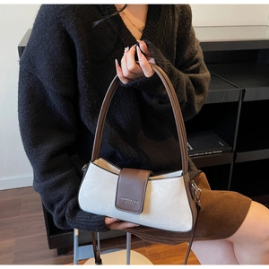 Close-up of minimalist cream and brown baguette bag with magnetic flap and logo
