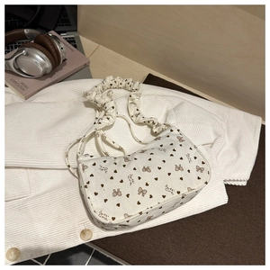 Detail of white corduroy shoulder bag featuring heart bow print and scrunchie strap style