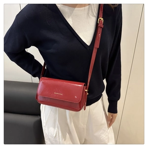 Close-up of a red glossy crossbody bag with golden KEKEDOU & BAG logo and hardware