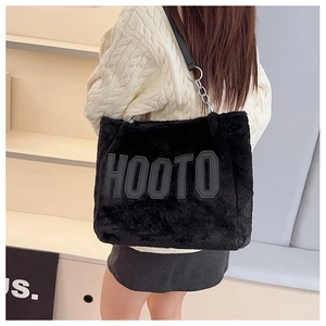 Detail showing plush faux fur texture and large gray HOOTO letter on black tote bag