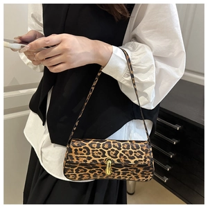 Detail of trendy leopard print baguette bag featuring a gold metal twist lock buckle