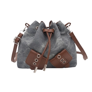 Chic denim drawstring bucket bag with brown leather trim and silver eyelet details