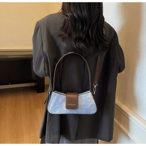 Detail of light blue velvet bag with brown leather flap and brand logo in a stylish outfit
