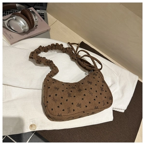 Close-up of brown corduroy crescent bag with black heart and bow prints and ruffled strap