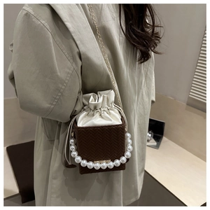 Detail of crossbody bag with herringbone weave, pearl handle and gold chain strap