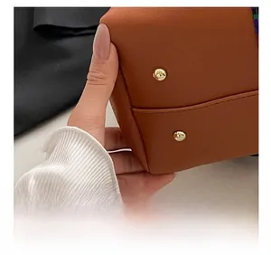 Close-up of brown leather bag base showing precision stitching and gold protective studs