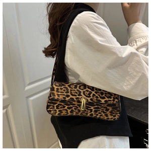 Detail of leopard print baguette bag with gold buckle on shoulder