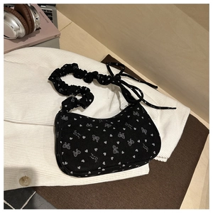 Detail of black corduroy shoulder bag with white bow prints and ruched strap design