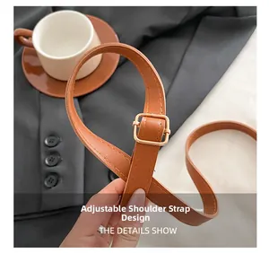 Close-up of adjustable brown leather shoulder strap with gold-tone buckle for handbag