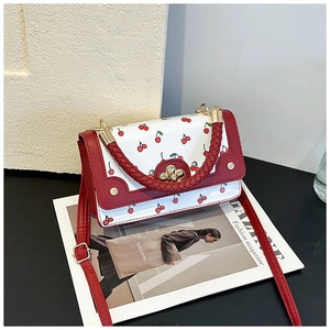 Detail of white cherry print handbag with red woven handle and gold floral twist lock