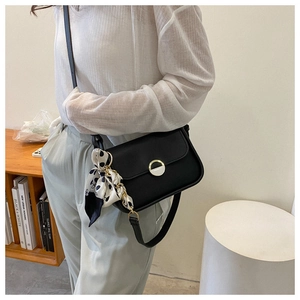 Detail of black leather shoulder bag featuring a polka dot silk scarf and gold magnetic clasp
