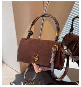 Detail of a brown faux suede handbag showing the golden twist lock and knot handle design