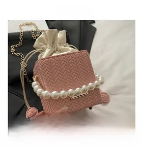 Pink woven bucket bag featuring elegant pearl handle and gold chain shoulder strap details