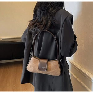 Detailed view of a vintage brown baguette bag with long straps worn on shoulder
