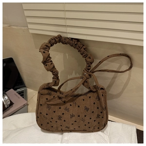 Close-up of brown corduroy handbag featuring black heart prints and ruffled handle details