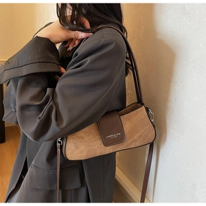 Close-up of brown leather and suede patchwork baguette bag with shoulder strap