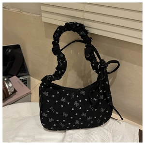 Detail of black corduroy handbag featuring white bow prints and ruffled handle