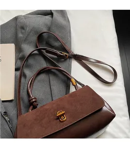 Detail view of the brown suede crossbody bag showing the gold buckle and leather strap