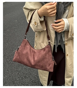 Macro detail of burgundy faux suede hobo bag with contrast stitching and brown handle