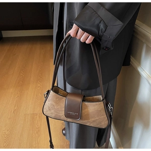 Close-up of retro brown shoulder bag featuring textured fabric and leather flap detail