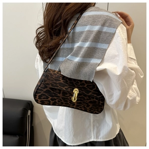 Detailed view of leopard print baguette bag with golden clasp worn over the shoulder