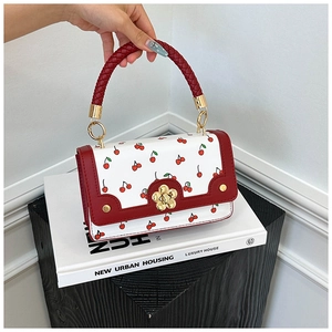 Close-up of leather crossbody bag with cherry prints and golden floral clasp