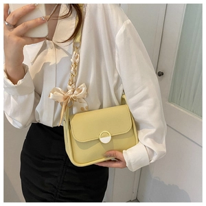 Chic yellow underarm bag featuring a decorative silk scarf on the shoulder strap
