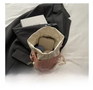 Pink woven bucket bag with large pearls showing spacious capacity for phone and makeup
