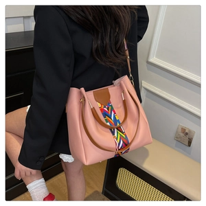 Close-up of pink tote bag with colorful woven strap and brown handles for daily use