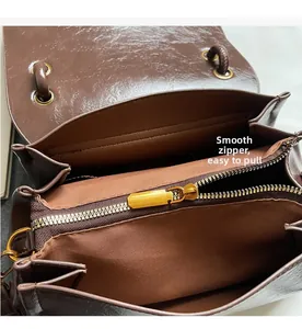 Detail of smooth gold zipper and interior lining of the brown suede crossbody bag