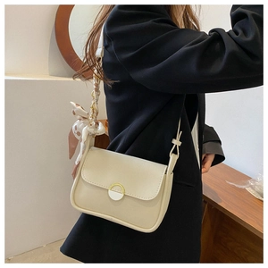 Detail of a creamy white flap crossbody bag with a decorative silk scarf and metal buckle