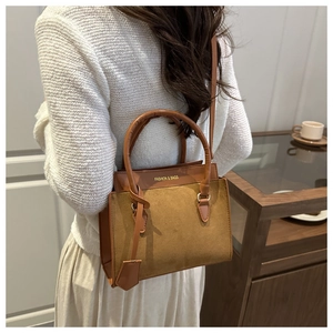 Sac bandoulière en cuir et daim marron porté par un mannequin en intérieur doux