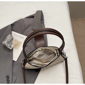 Top view of two-tone handbag with beige body, brown straps, and spacious inner zipper pocket