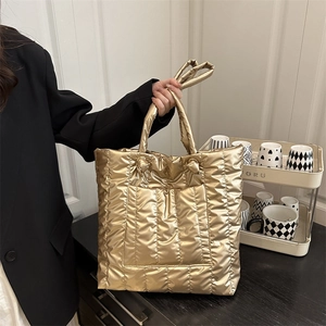 Chic gold metallic quilted tote bag with padded puffer design for a luxury fashion look