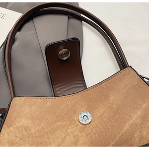 Macro detail of brown textured fabric handbag with magnetic closure and leather piping